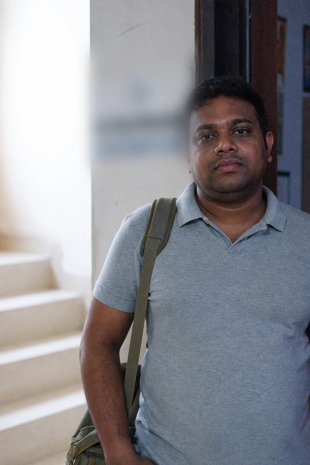 Dr Kiran Marreddy standing in the clinic doorway with a kit bag on his shoulder, looking at the camera.
